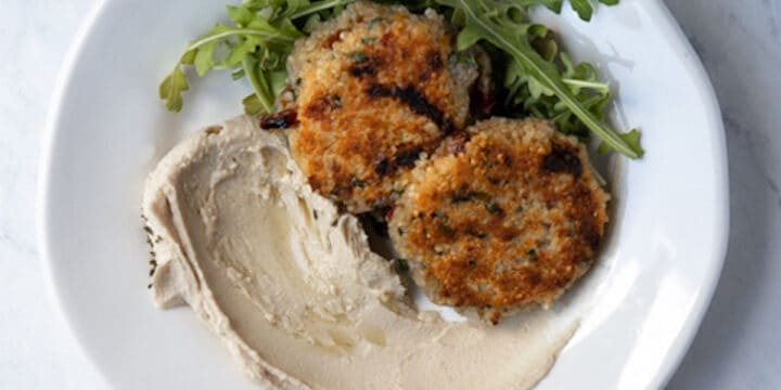 overhead photo of quinoa patties on a plate with hummus