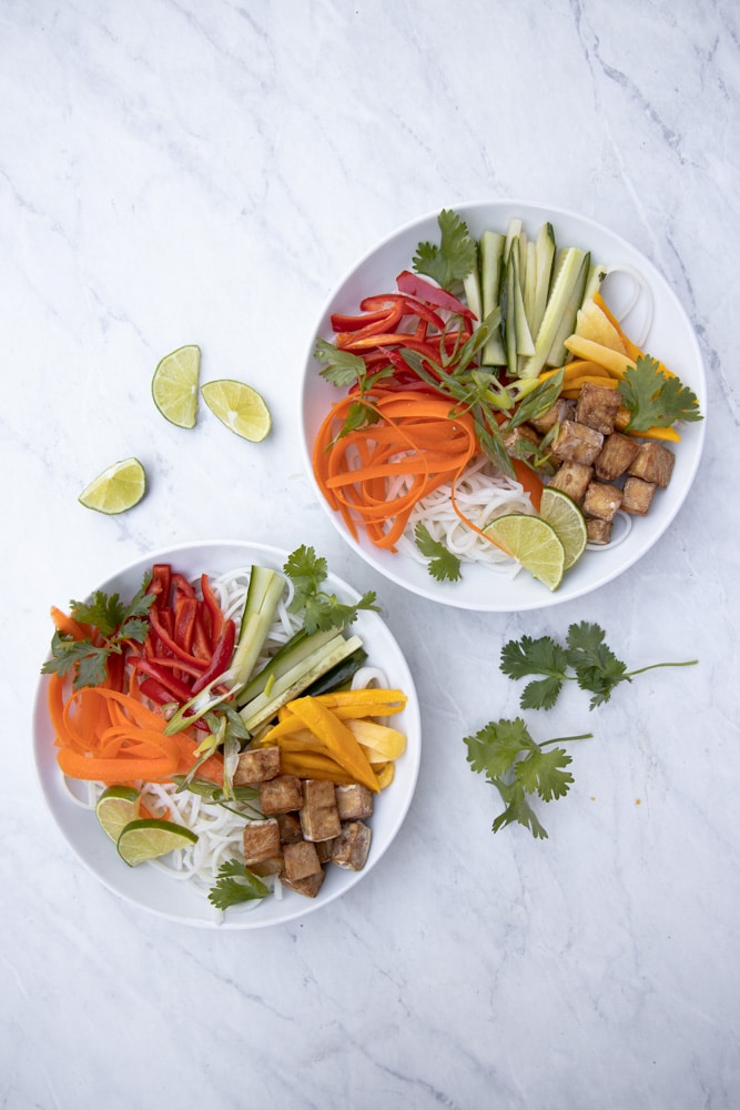 overhead photo of bowl of noodles with carrots, cucumber, mango, bell pepper and tofu