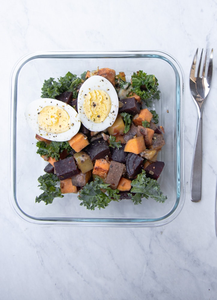 glass container with root vegetable hash and a hard boiled egg on top