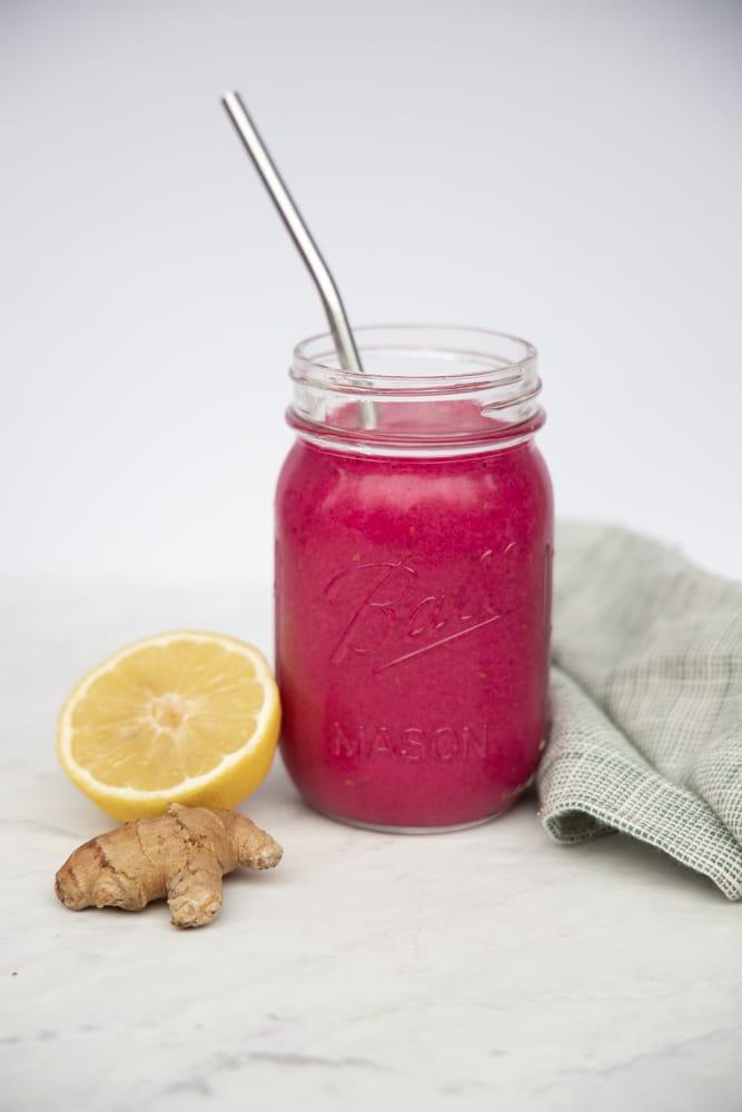 beet smoothie in a glass jar with a metal straw