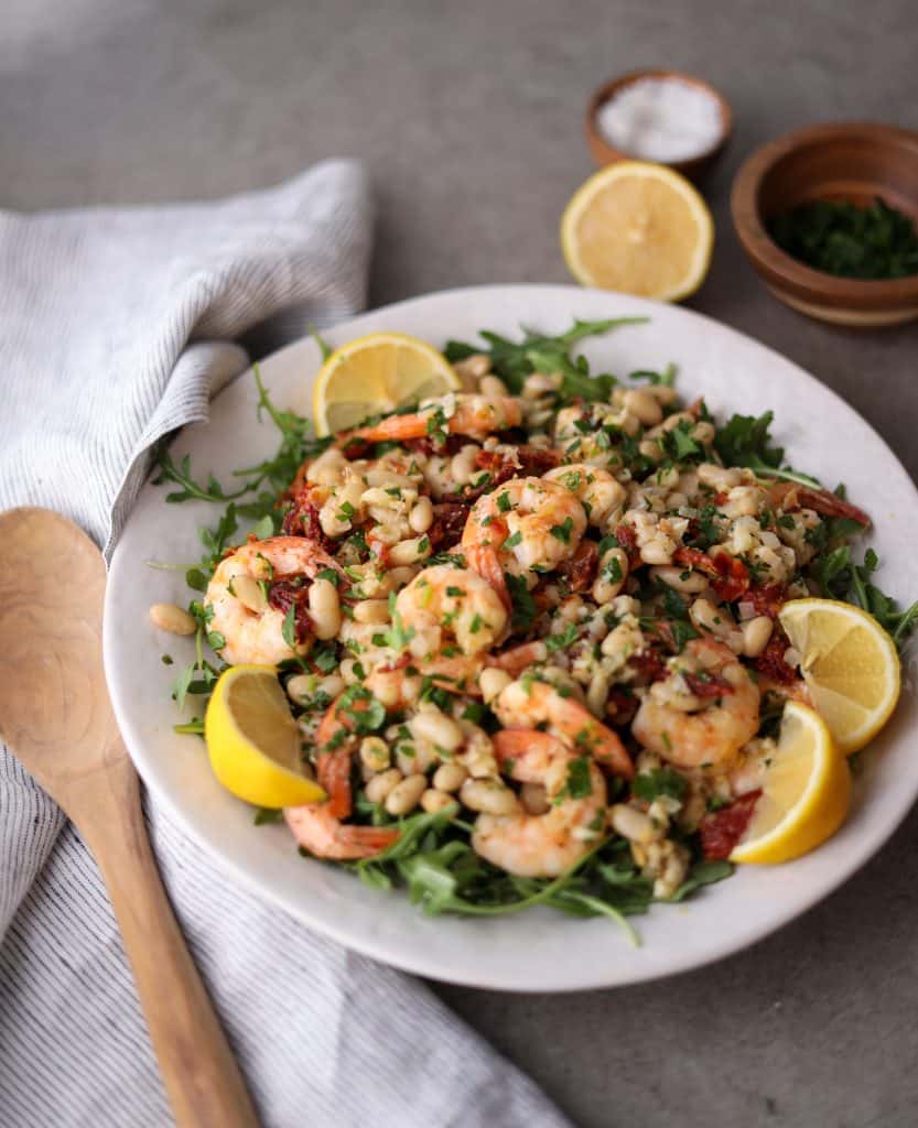 mediterranean shrimp salad on a platter with lemon wedges