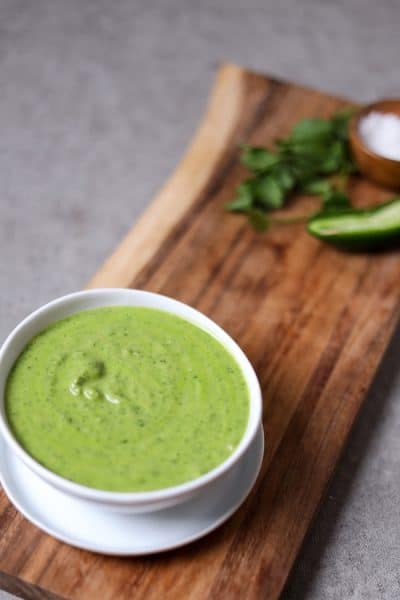 bowl of cilantro jalapeno sauce on a wood cutting board