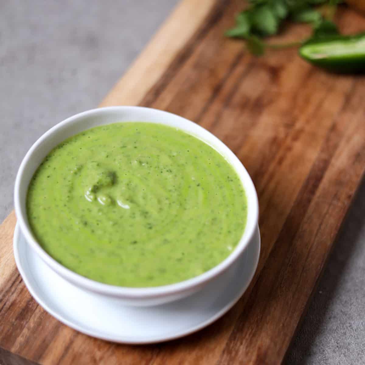 bowl of cilantro jalapeño sauce on wood cutting board