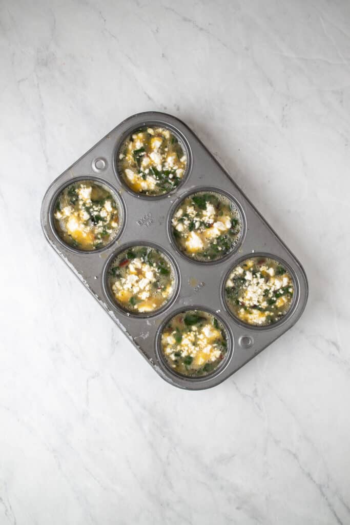 uncooked egg bites in a metal muffin tin