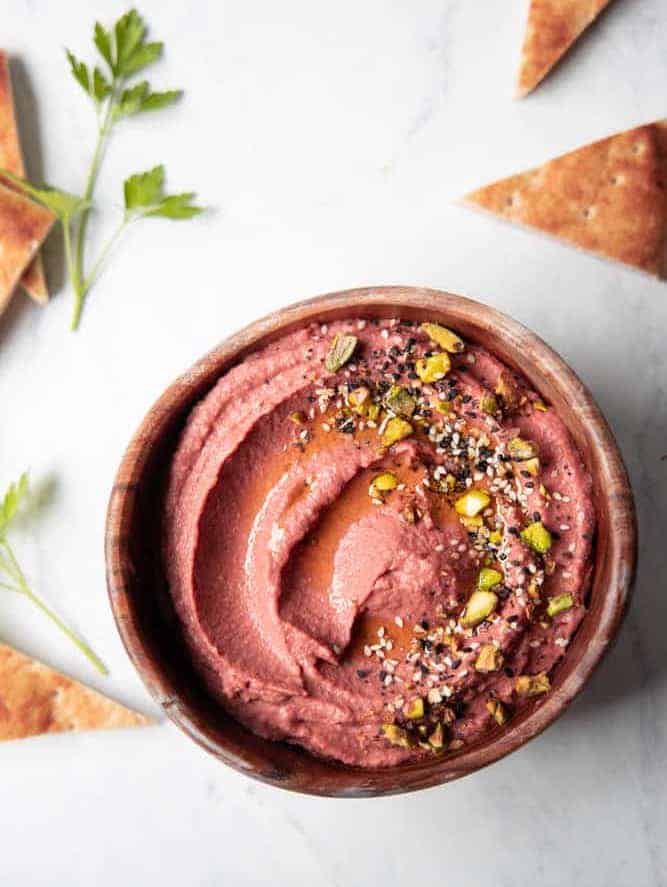 lemon beet hummus in a bowl with pistachios sprinkled on top