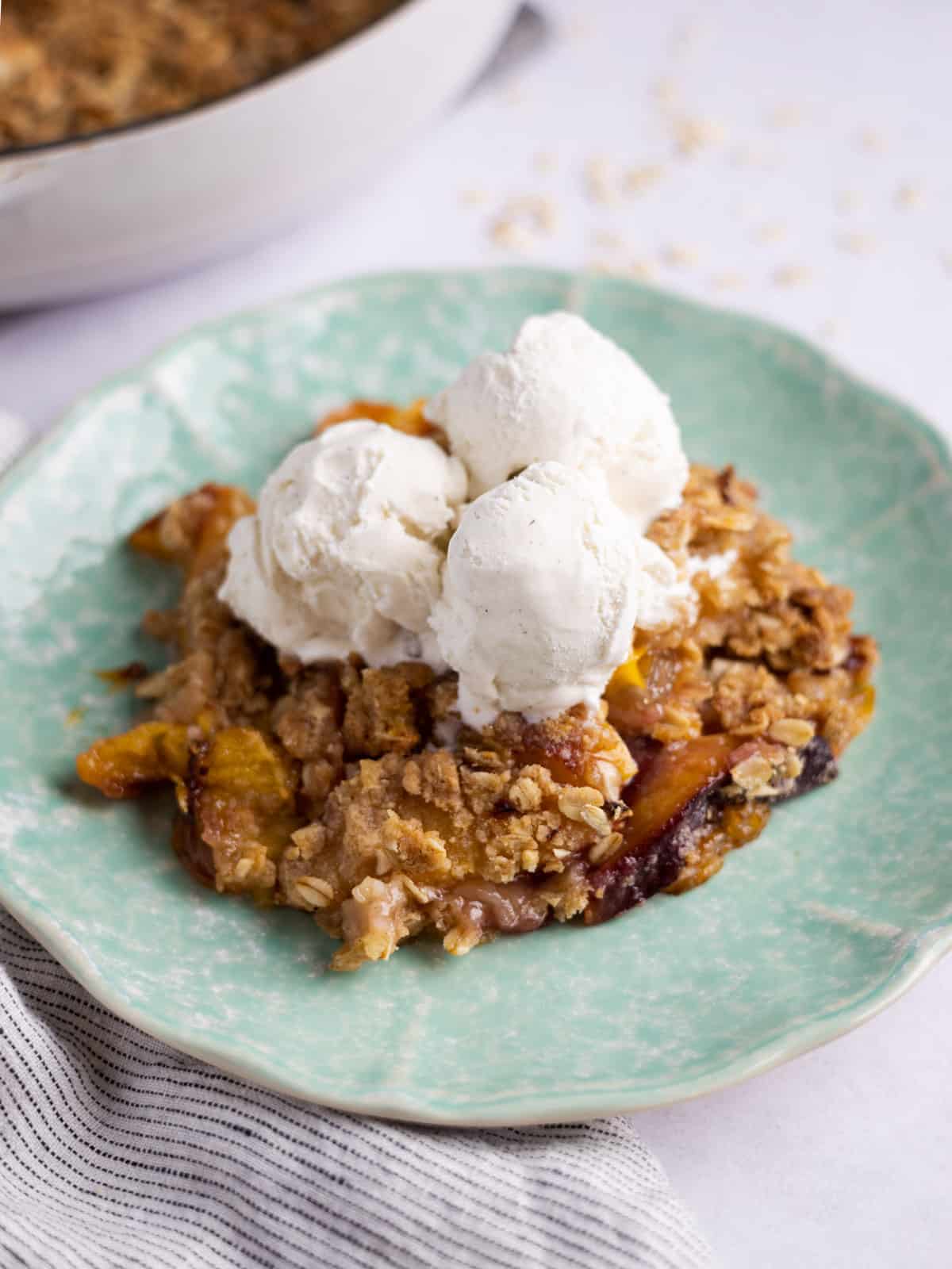 close up of nectarine crumble with vanilla ice cream on top