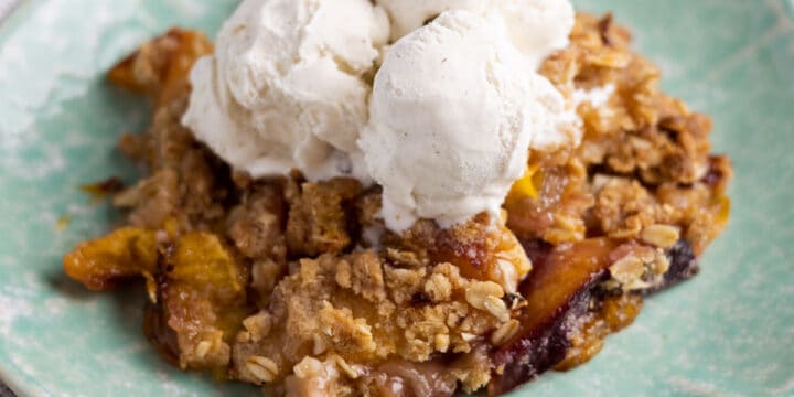 nectarine crumble on a plate with scoops of vanilla ice cream on top