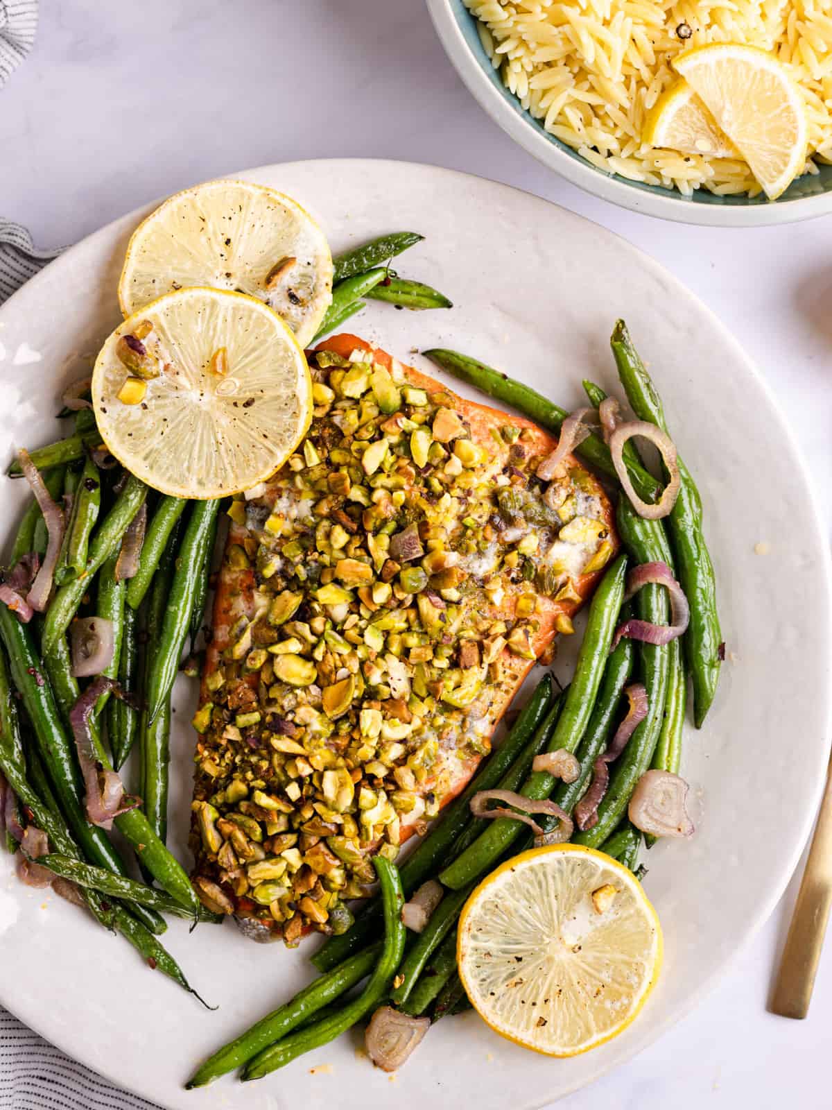 salmon topped with pistachio crust and served with green beans on a platter