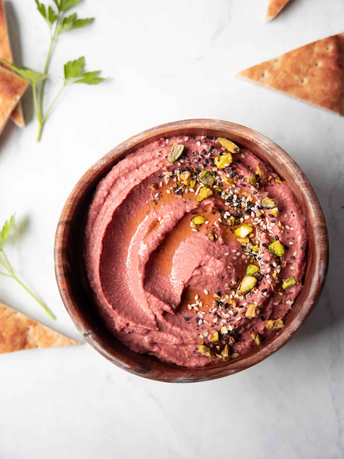 lemon beet hummus in a bowl topped with pistachios