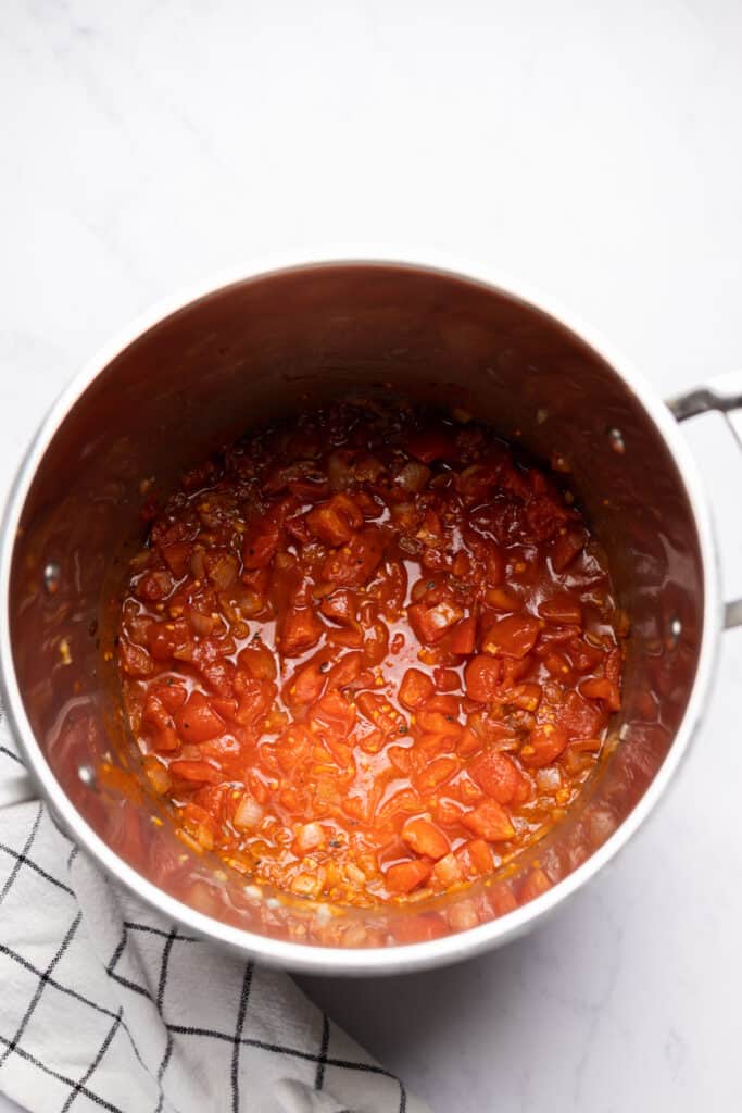 Diced tomatoes added to soup pot.