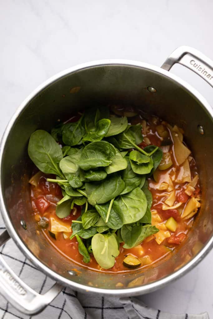 Lasagna soup in a pot with spinach added.