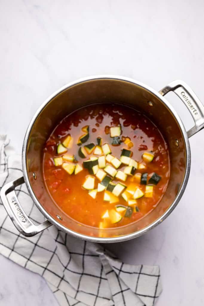 soup in a pot with zucchini added.
