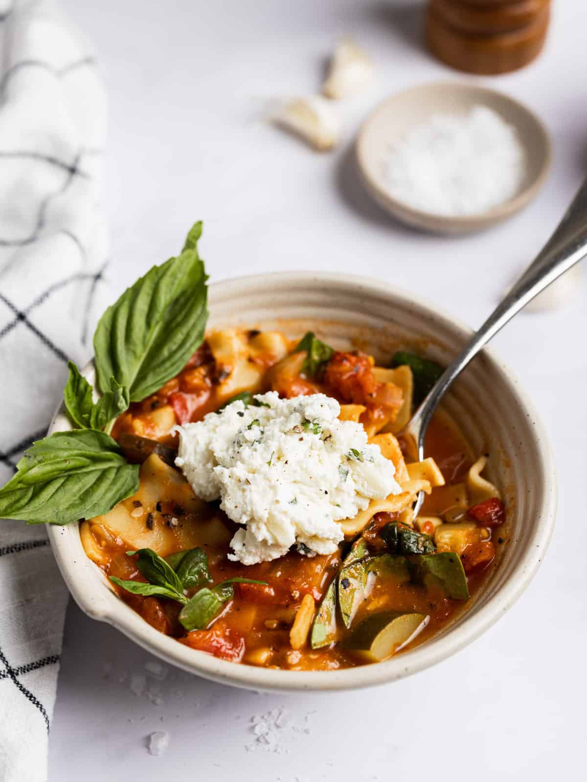 Vegetarian lasagna soup in a bowl with ricotta cheese mix dolloped on top.