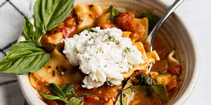 Vegetarian lasagna soup in a bowl with ricotta cheese on top.