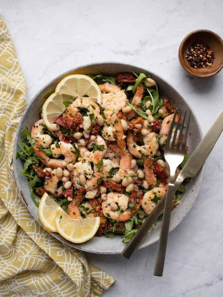 shrimp salad in a bowl with sliced fresh lemon on top