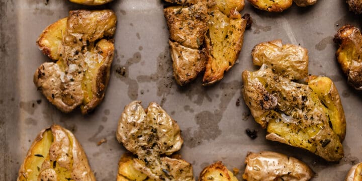 Golden brown smashed fingerling potatoes on a cookie sheet.