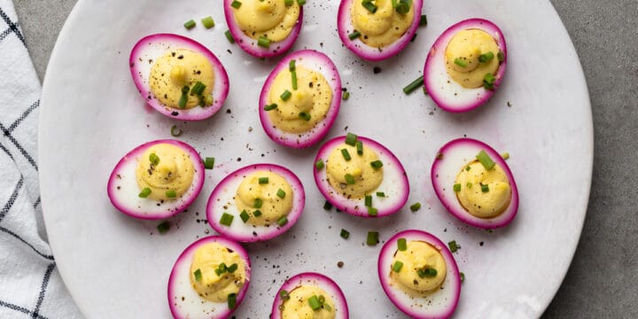 Beet deviled eggs arranged on a white serving platter.