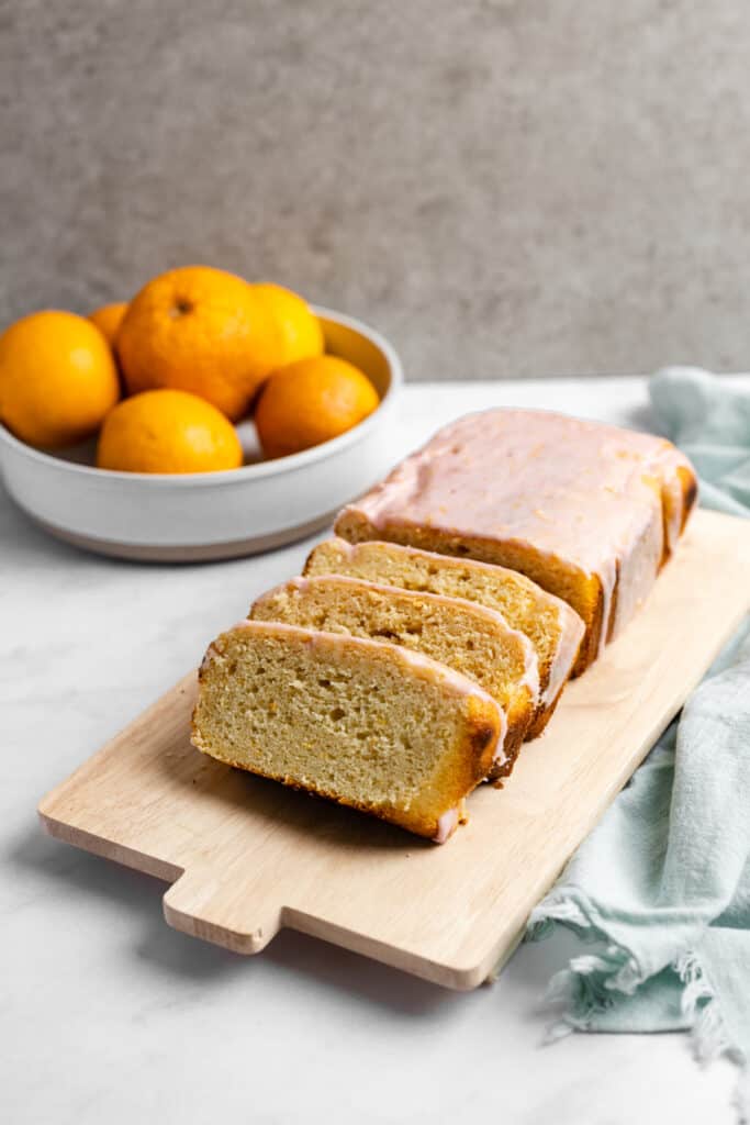 Blood orange yogurt loaf sliced on a cutting board.