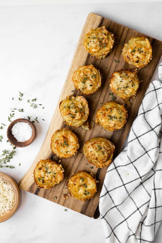 Cheesy gruyere and potato stacks on a wooden platter.