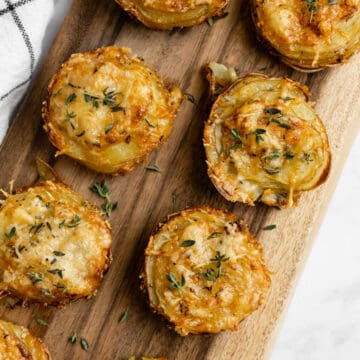 Stacks of potato and gruyere on a cutting board.