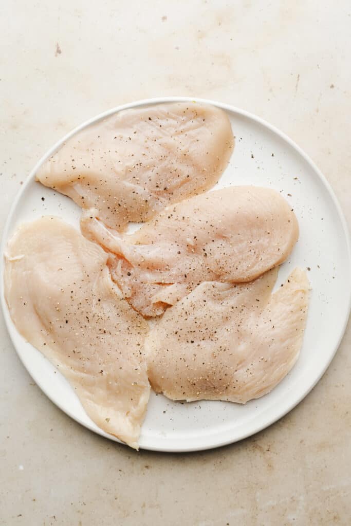 Thin cut chicen breasts on a plate.
