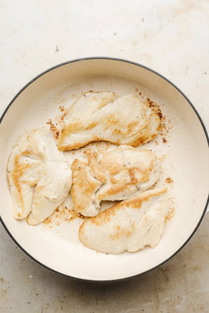 Browned chicken breasts in a skillet.