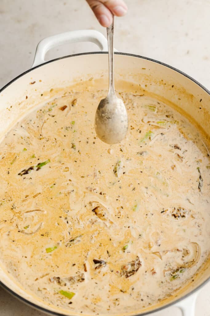 Creamy sun dried tomato sauce coating the back of a spoon.