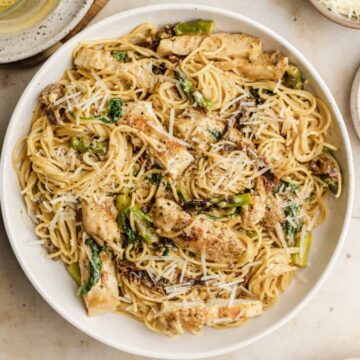 Sundried tomato pasta chicken in a white serving bowl topped with parmesan cheese.