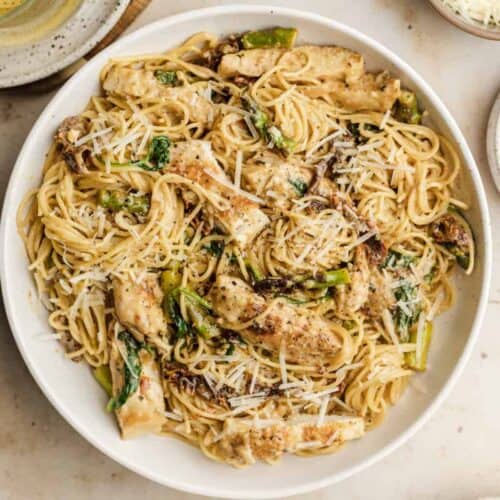 Sundried tomato pasta chicken in a white serving bowl topped with parmesan cheese.