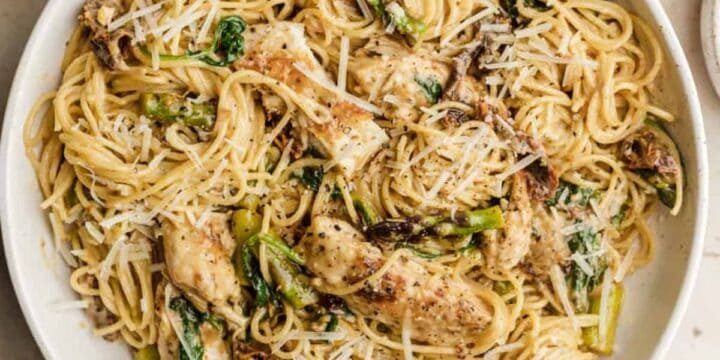 Sundried tomato pasta chicken in a white serving bowl topped with parmesan cheese.